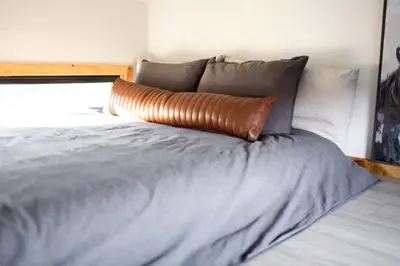 a bed with a brown pillow on top of it at Unplug in a Rustic-Chic Tiny Home: Stargazing Patio, Cookout Space & Nature Views in Aguanga, California in Aguanga