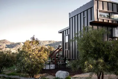 a black house with a view of the mountains at Unplug in a Rustic-Chic Tiny Home: Stargazing Patio, Cookout Space & Nature Views in Aguanga, California in Aguanga
