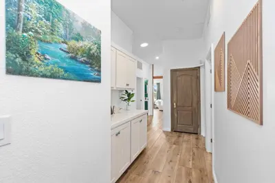 a kitchen with white cabinets and a painting on the wall at Avocado Akres Awaits Near Monserate Winery in Fallbrook