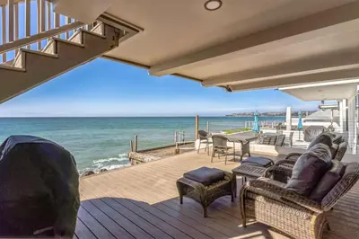 a deck with chairs and a table and the ocean at 450A Ocean View beach house in Dana Point