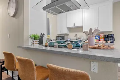 a kitchen with white cabinets and a counter with chairs at Entire Private Home with 2 Bedrooms 1 Bathroom, King Bed, Pool, Hot Tub, 2 Parking in Mira Mesa Available Now in San Diego