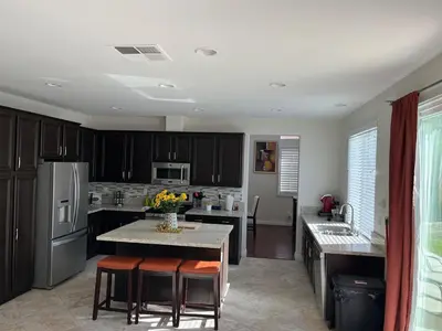 a kitchen with black cabinets and a kitchen island with stools at Modern Family Oasis in San Jacinto