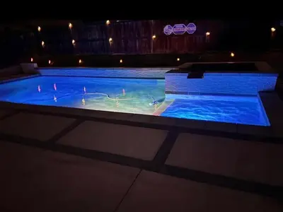 a large swimming pool with people in it at night at Modern Family Oasis in San Jacinto