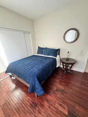 a bedroom with a bed with a blue blanket and a table at Modern Family Oasis in San Jacinto