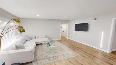a living room with a white couch and a flat screen tv at Spacious 4BR Loft - Outdoor Movie Theater in El Cajon