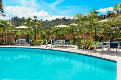 a swimming pool with chairs and tables and umbrellas at SpringHill Suites by Marriott San Diego Mission Valley in San Diego