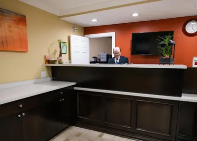 a man standing at a reception counter in a waiting room at Scandia Motel in Carlsbad