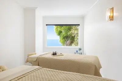 a white room with two beds and a window at Surf & Sand Laguna Beach in Laguna Beach