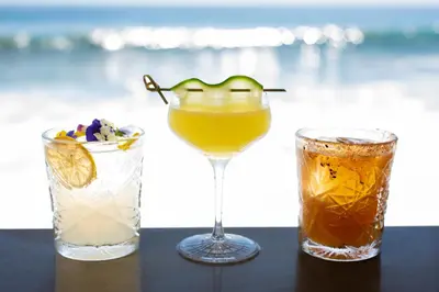 three cocktails sitting on a table with a drink at Surf & Sand Laguna Beach in Laguna Beach