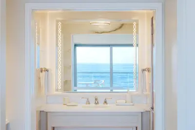 a bathroom with a sink and a mirror with a window at Surf & Sand Laguna Beach in Laguna Beach