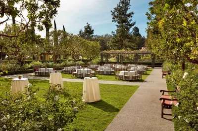 a restaurant with white tables and chairs in a garden at Rancho Bernardo Inn in Rancho Bernardo
