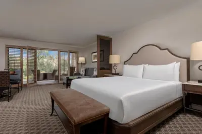 a bedroom with a large white bed and a living room at Rancho Bernardo Inn in Rancho Bernardo