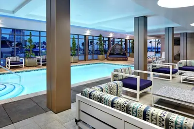 a pool in a hotel with lounge chairs and tables at Hilton Garden Inn San Diego Downtown/Bayside, CA in San Diego