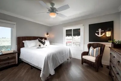 a bedroom with a bed with a ceiling fan and a chair at Newport Beach Hotel in Newport Beach