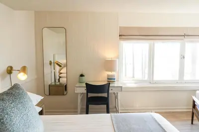 a bedroom with a bed and a desk and a mirror at Newport Beach Hotel in Newport Beach