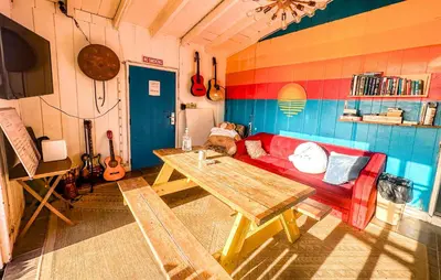 a living room with a red couch and a table at ITH San Diego Beach Bungalow Surf Hostel in San Diego