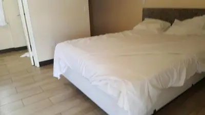 a white bed in a bedroom with a wooden floor at Ace Budget Motel in San Diego