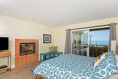 a bedroom with a bed and a fireplace and a television at Ocean View Steps to Beach M-C in Oceanside