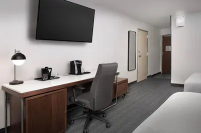 a room with a desk with a chair and a tv on the wall at Courtyard by Marriott San Diego Carlsbad in Carlsbad