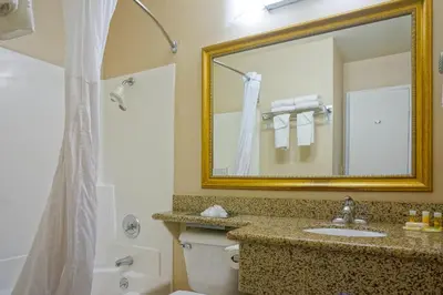 a bathroom with a sink and a mirror and a toilet at Days Inn by Wyndham Mission Valley-SDSU in San Diego