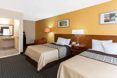 a hotel room with two beds and a chair at Days Inn by Wyndham Mission Valley-SDSU in San Diego