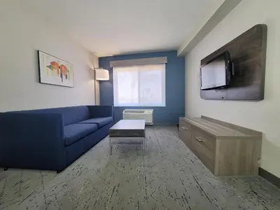a living room with a blue couch and a tv at Holiday Inn Express San Diego South - Chula Vista by IHG in Chula Vista