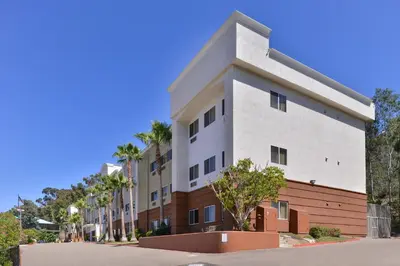 a building on a street with palm trees at Candlewood Suites San Diego by IHG in San Diego
