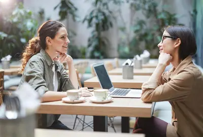 two women sitting at a table with a laptop at Motel 6 Lake Elsinore, CA in Lake Elsinore