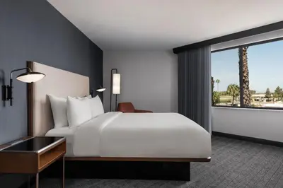 a bedroom with a white bed and a large window at Courtyard by Marriott San Diego Miramar in San Diego