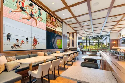 a restaurant with tables and chairs and a large painting of people playing volleyball at Hilton San Diego Bayfront in San Diego