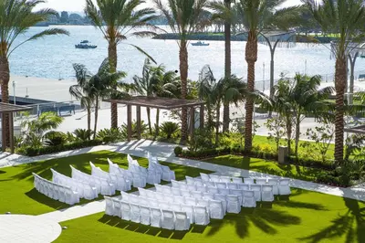 an outdoor wedding with white chairs and palm trees at Hilton San Diego Bayfront in San Diego
