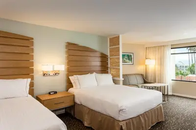a hotel room with two beds and a chair at Holiday Inn Express and Suites La Jolla - Windansea Beach, and IHG Hotel in San Diego