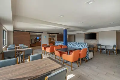 a waiting room with tables and chairs and a tv at Holiday Inn Express San Diego South - National City by IHG in National City