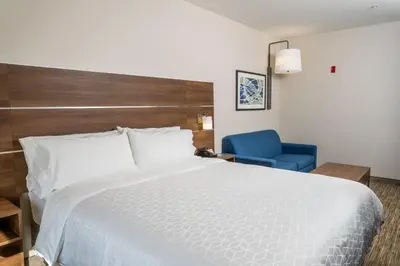 a bedroom with a large white bed and a blue chair at Holiday Inn Express San Clemente N – Beach Area by IHG in San Clemente