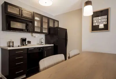 a kitchen with a table and a black refrigerator at Sonesta Simply Suites Irvine East Foothill in Lake Forest