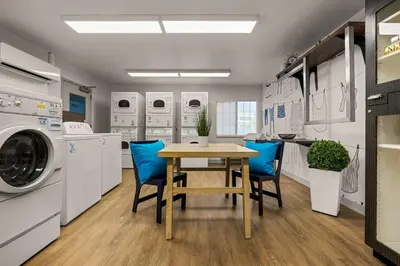a laundry room with a table and blue chairs at Sonesta Simply Suites Irvine East Foothill in Lake Forest