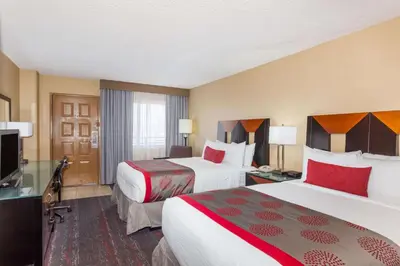 a hotel room with two beds and a television at Ramada by Wyndham San Diego National City in National City