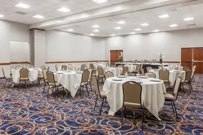 a conference room with tables and chairs and a screen at Ramada by Wyndham San Diego National City in National City