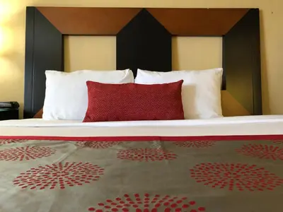 a bed with two pillows and a red pillow at Ramada by Wyndham San Diego National City in National City
