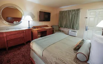 a hotel room with a bed and a desk and a mirror at Heritage Inn La Mesa in La Mesa