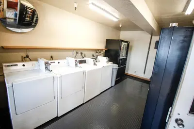 a laundry room with three washing machines and a sink at Heritage Inn La Mesa in La Mesa
