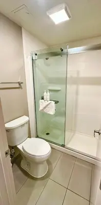a bathroom with a toilet and a glass shower at Heritage Inn San Diego in San Diego