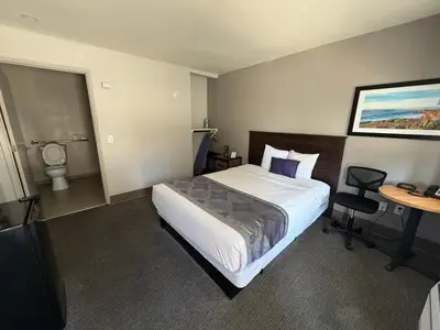 a hotel room with a bed and a desk and a table at Heritage Inn San Diego in San Diego
