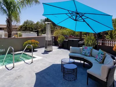 a patio with a couch and an umbrella and a pool at Holiday Inn Express Hotel & Suites Solana Beach-Del Mar by IHG in Solana Beach