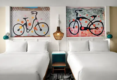 two beds in a room with paintings on the wall at Holiday Inn Express Hotel & Suites Solana Beach-Del Mar by IHG in Solana Beach