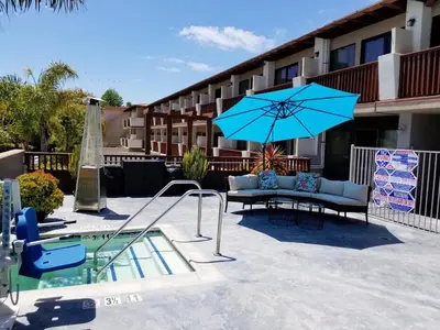 a patio with a blue umbrella next to a pool at Holiday Inn Express Hotel & Suites Solana Beach-Del Mar by IHG in Solana Beach