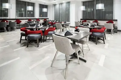 a dining room with tables and red chairs at Hilton Garden Inn Irvine Spectrum Lake Forest in Lake Forest