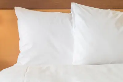 a bed with white sheets and pillows on it at Holiday Inn Express Newport Beach by IHG in Newport Beach