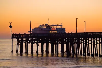 a pier with a boat in the water at sunset at Holiday Inn Express Newport Beach by IHG in Newport Beach