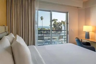 a bedroom with a bed and a view of the ocean at Hilton Garden Inn Dana Point Doheny Beach in Dana Point